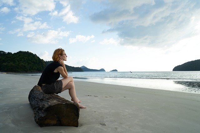 Woman Sitting Alone On A Log By The Water