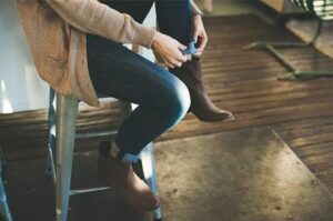 person on a stool cuffing their jeans