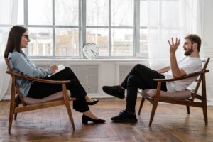 woman and man sitting in chairs across from one another, talking