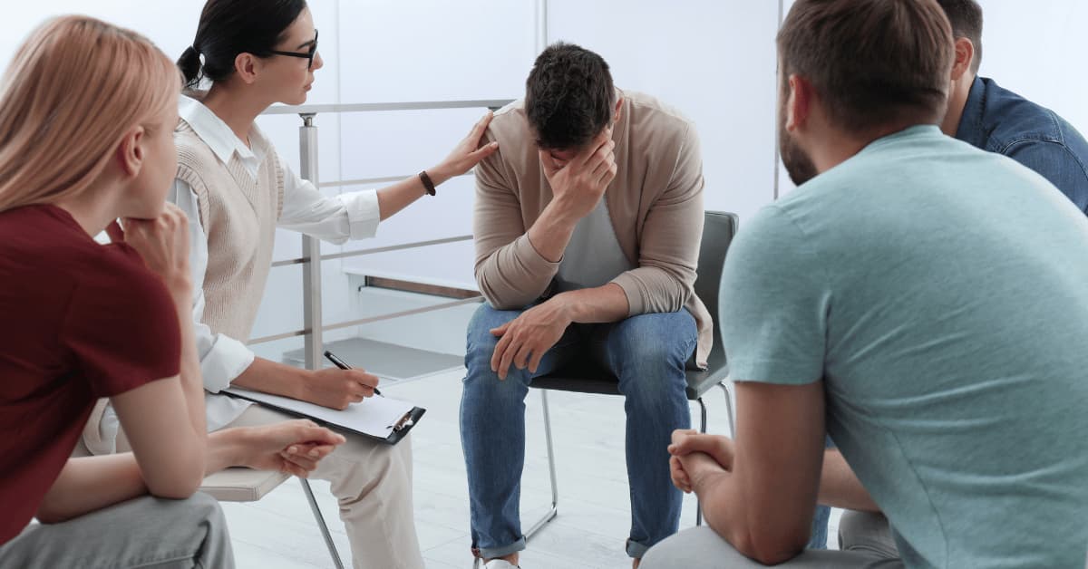 Man in group with head down